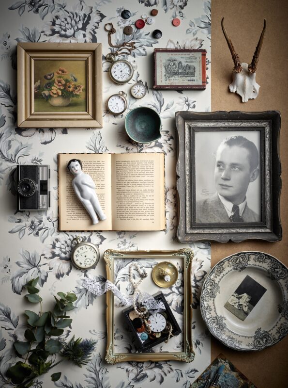 Tavlor, böcker, porslin på ljus tapet, flatlay. Studiofoto Sandberg Wallpaper