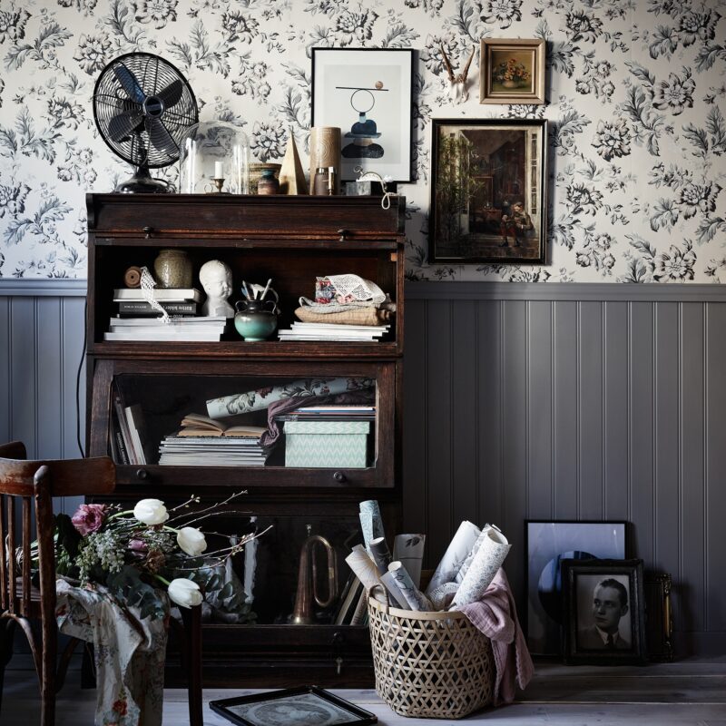 Byrå i mörkt trä, vägg med mönstrad tapet och grå bröstpanel. Studiofoto Sandberg Wallpaper