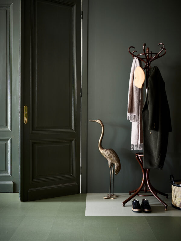 Grön målad vägg och pardörr, kläder hängande på tamburmajor Locationfotografering av Marmoleum clickgolv för Forbo Flooring hos Östlinghs Inredning i Spinneriet, Lindome