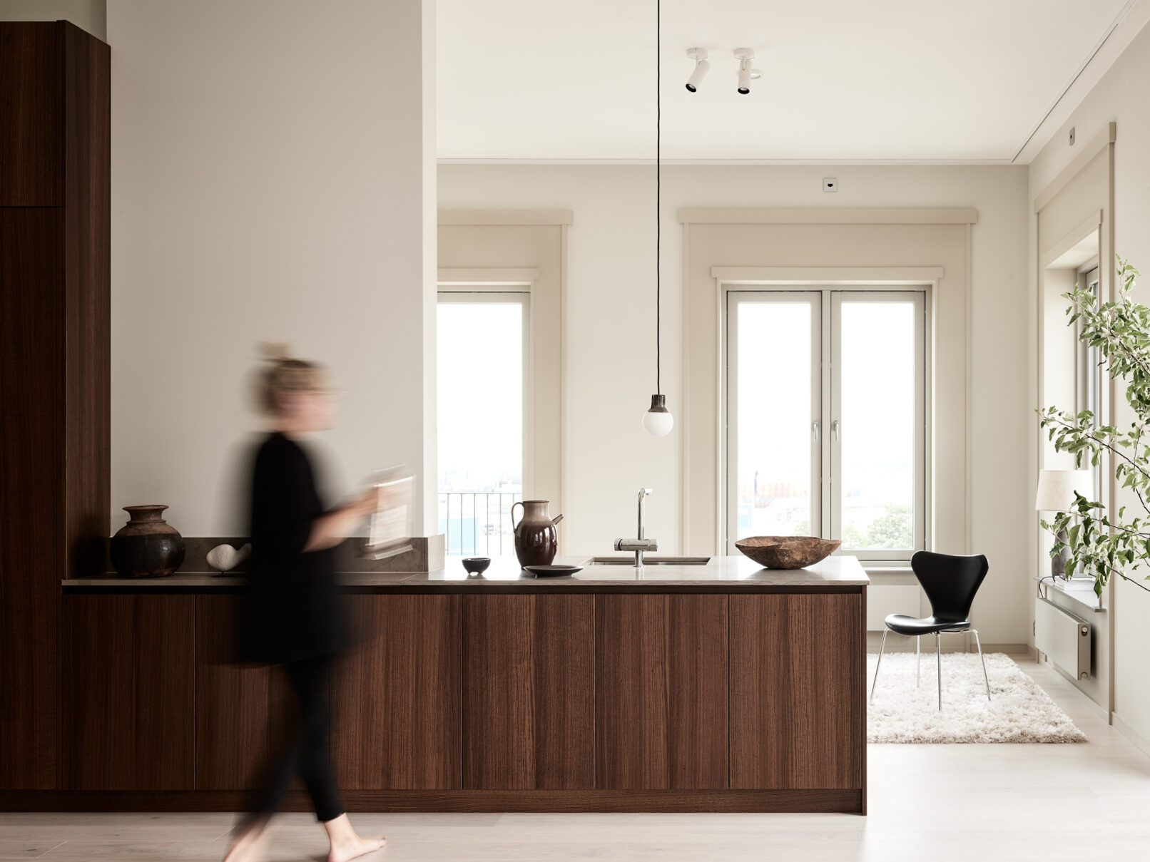 En kvinna navigerar graciöst genom ett fascinerande designat Kvänum kök, elegant fångat i ett interiörfotografi.