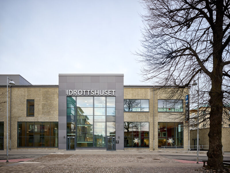 Framsidan av Idrottshuset i Jönköping visar upp sin imponerande arkitektur med ett träd i förgrunden.