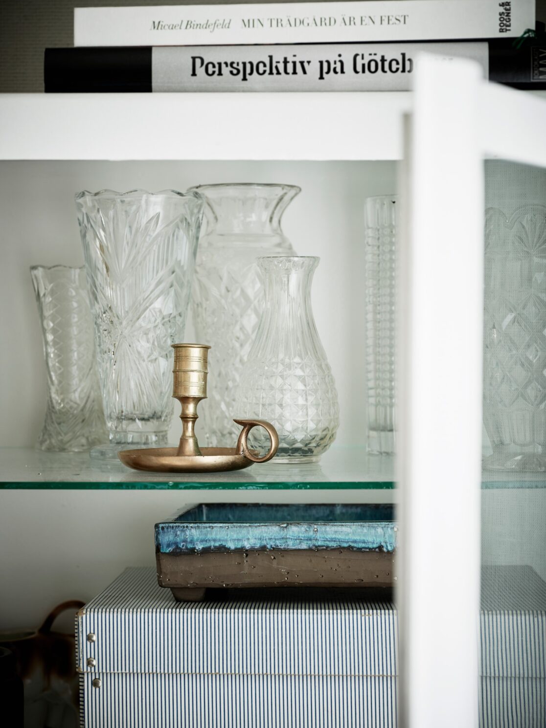 Detaljbild på ljusstake och glaskaraffer i ett vitrinskåp. Foto av Jonas Berg