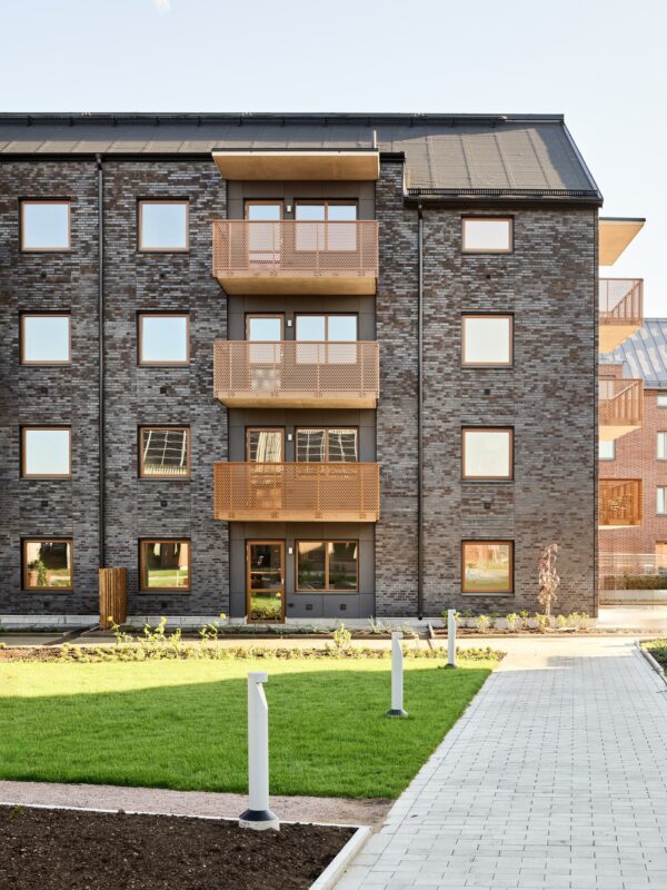 Fasadbild arkitektur med grön gräsmatta i förgrunden. Ranalyckan, ett kvarter i stadsdelen Ranagård i Halmstad.