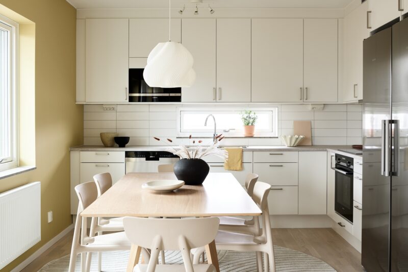 Kök med gula väggar. Interiörfotografering av visningslägenhet i det nybyggda bostadsprojektet Ranalyckan, ett kvarter i stadsdelen Ranagård i Halmstad för Skanska Bostad.