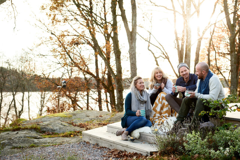 Personer som fikar utomhus på ett trädäck i motljus, höst