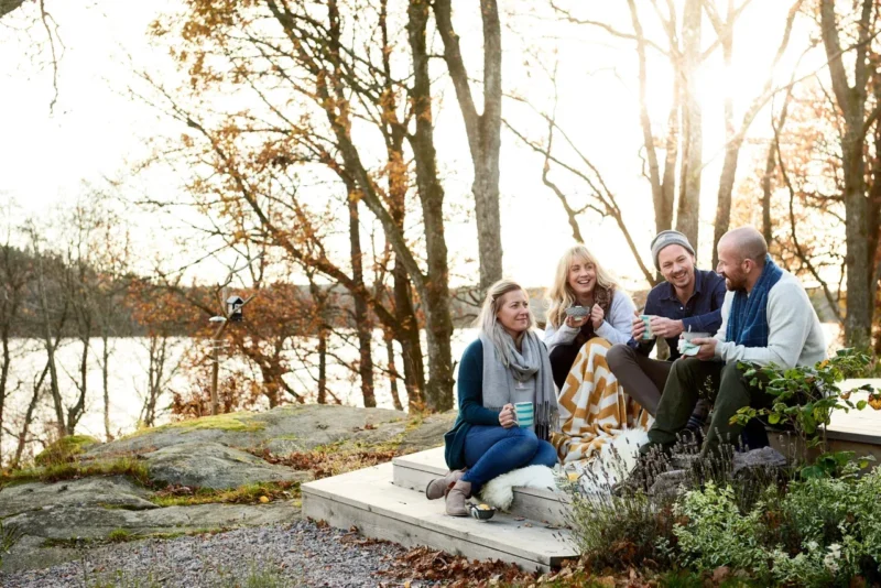 Personer som fikar utomhus på ett trädäck i motljus, höst